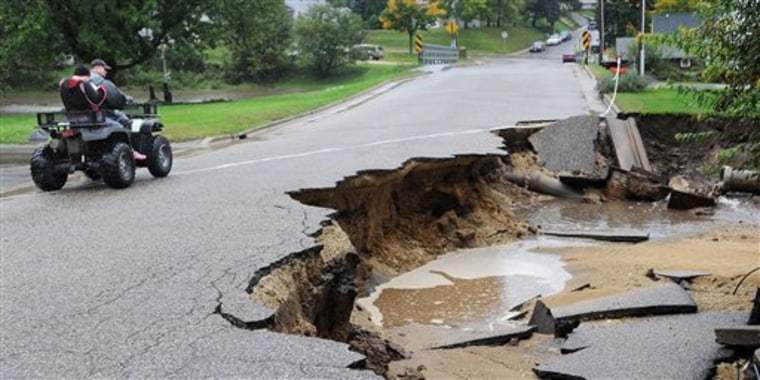 Mark Finner and his daughter, Kayla, drive past a damaged road along Oak Street in Arcadia, Wis. on Thursday, Sept. 23, 2010. A state of emergency was declared for the Trempealeau County community after heavy rains flooded the area. (AP Photo/Eau Claire Leader-Telegram, Dan Reiland)